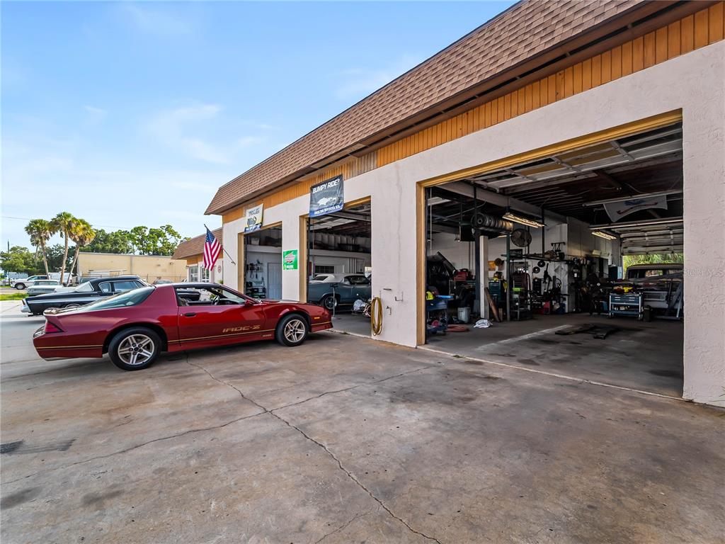 A red IROC-Z parked outside an auto repair shop with open garage bays — 101 S INDIANA AVENUE, ENGLEWOOD, FL