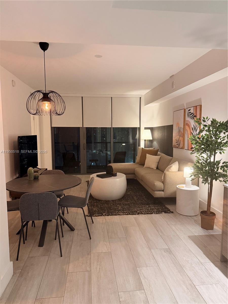 A modern living and dining area features light wood floors, neutral furniture, and floor-to-ceiling windows — 121 NE 34th St # 2806A, Miami FL 33137, MIAMI, FL