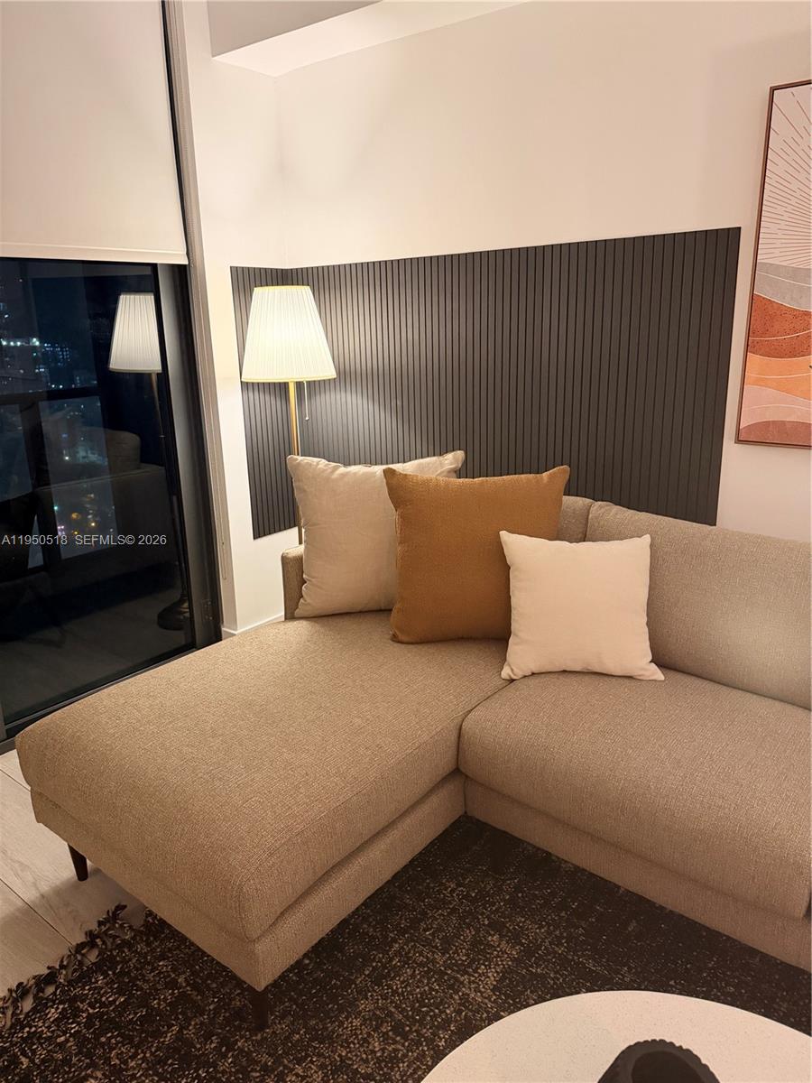 A sectional sofa with decorative pillows sits in a living room with slatted wall paneling — 121 NE 34th St # 2806A, Miami FL 33137, MIAMI, FL