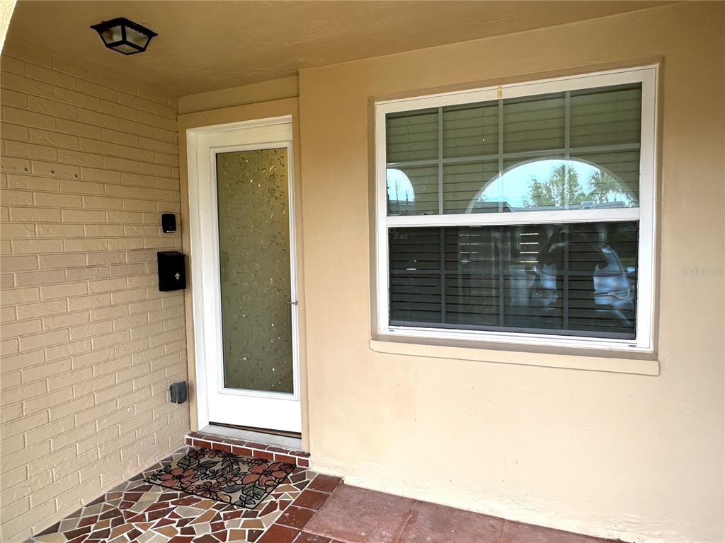 A tan brick exterior wall features a white front door and a large window — 4211 STRATFORD DRIVE UNIT 4211, NEW PORT RICHEY, FL