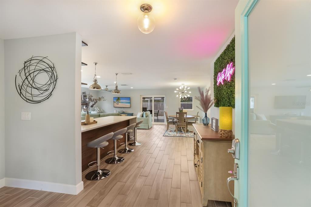 An open-concept living area features a kitchen island with bar stools, dining space, and flooring — 5720 ISANDA PLACE, SARASOTA, FL