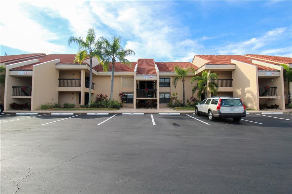 A multi-story apartment building with a tiled roof and a parking lot in the foreground — 3256 WHITE IBIS COURT UNIT 27, PUNTA GORDA, FL