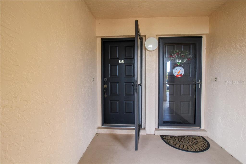 Two black front doors with screen doors are set into a beige stucco entryway — 3256 WHITE IBIS COURT UNIT 27, PUNTA GORDA, FL