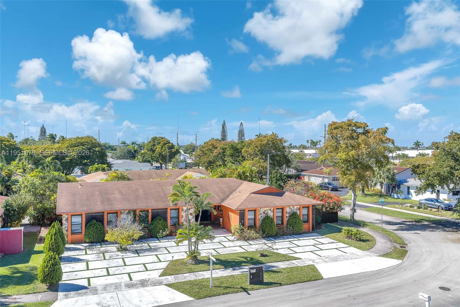 An orange single-story house with a paved driveway sits on a corner lot — 21424 NE 19th Ct, Miami FL 33179, MIAMI, FL