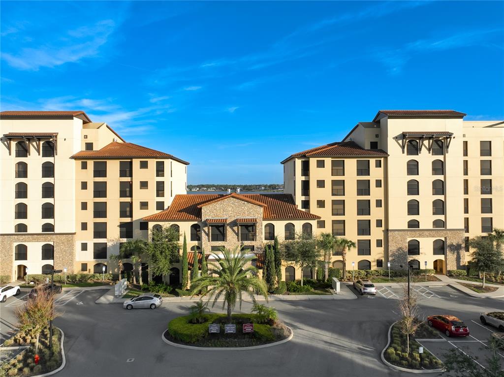 An exterior view of a multi-story apartment complex with a central courtyard and parking lot — 16300 COUNTY ROAD 455 UNIT 306, MONTVERDE, FL