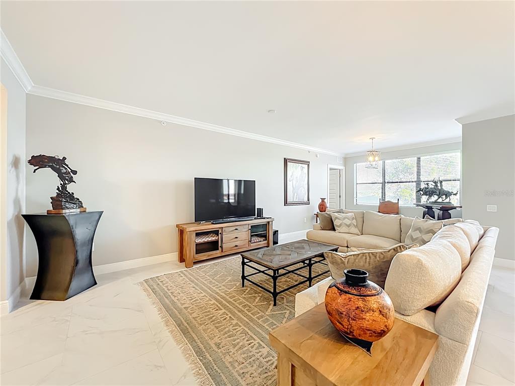 A living room features a sectional sofa, a television on a wooden console, and tile flooring — 16300 COUNTY ROAD 455 UNIT 306, MONTVERDE, FL