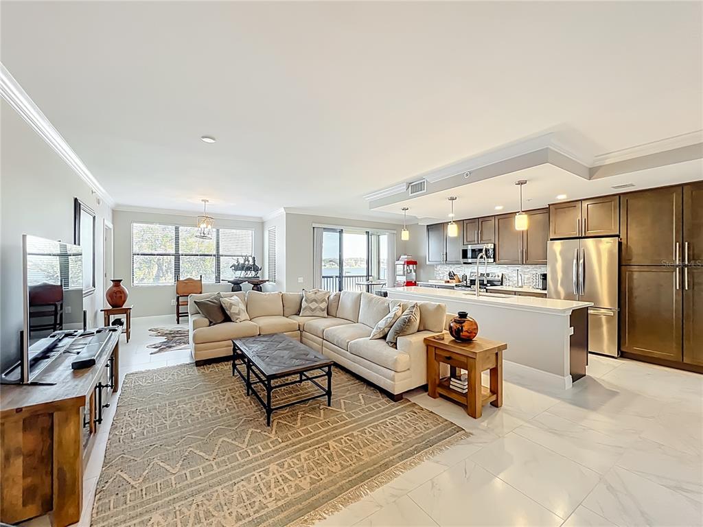 An open-concept living room and kitchen featuring a sectional sofa, tile floors, and stainless appliances — 16300 COUNTY ROAD 455 UNIT 306, MONTVERDE, FL