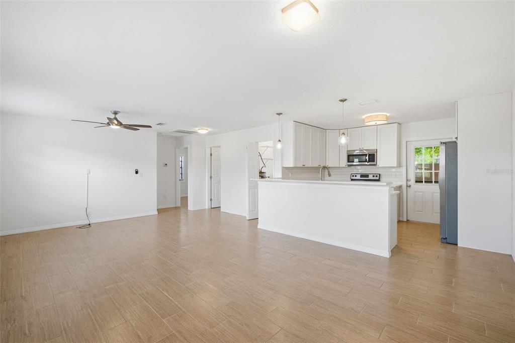 An open-concept living and dining area features a white sofa, round wooden table, and kitchen — 4110 W LEILA AVENUE, TAMPA, FL