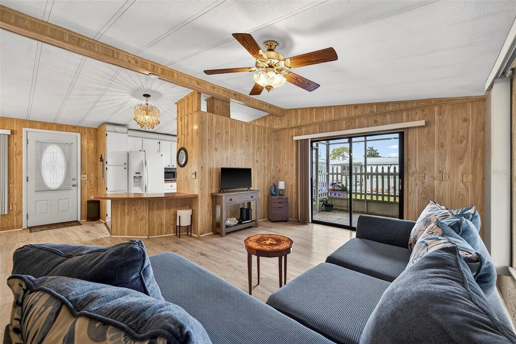 A living room features wood-paneled walls, a ceiling fan, and a view of a patio — 7880 54TH AVENUE N UNIT 38, ST PETERSBURG, FL