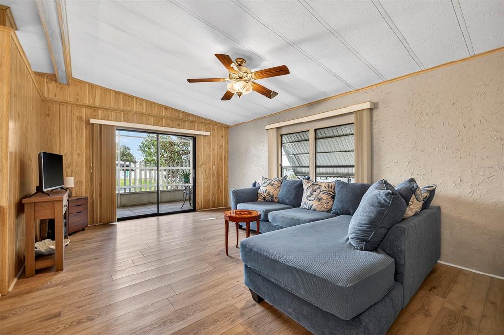 A living room features wood-paneled walls, a blue sectional sofa, and a sliding glass door — 7880 54TH AVENUE N UNIT 38, ST PETERSBURG, FL
