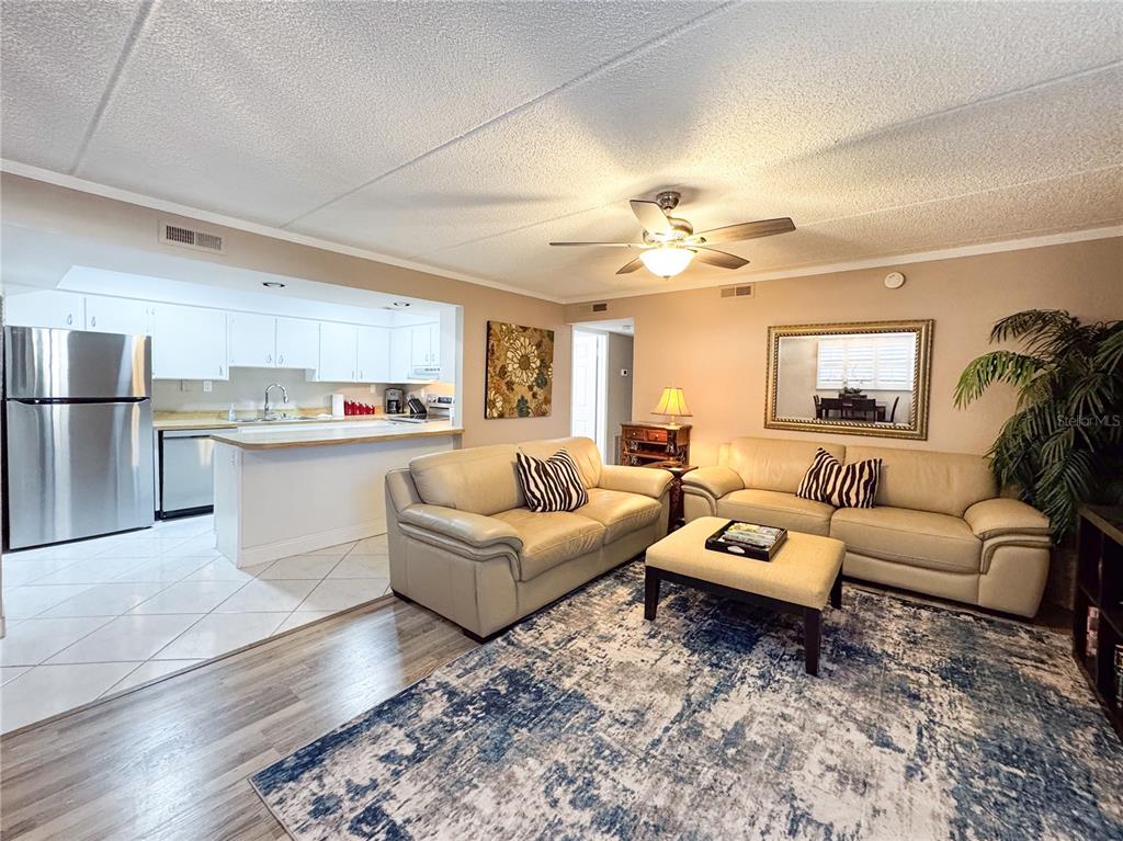 A living room with beige sofas, a blue patterned rug, and an open-concept kitchen — 12760 INDIAN ROCKS ROAD UNIT 510, LARGO, FL