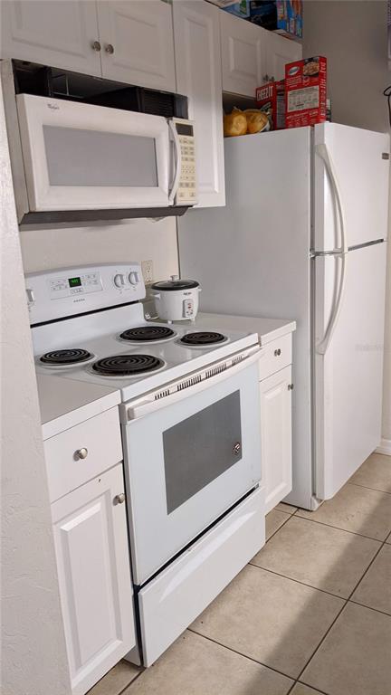 A kitchen features white cabinets, a white stove, a microwave, and a white refrigerator — 4000 SW 23RD STREET UNIT 3-107, GAINESVILLE, FL