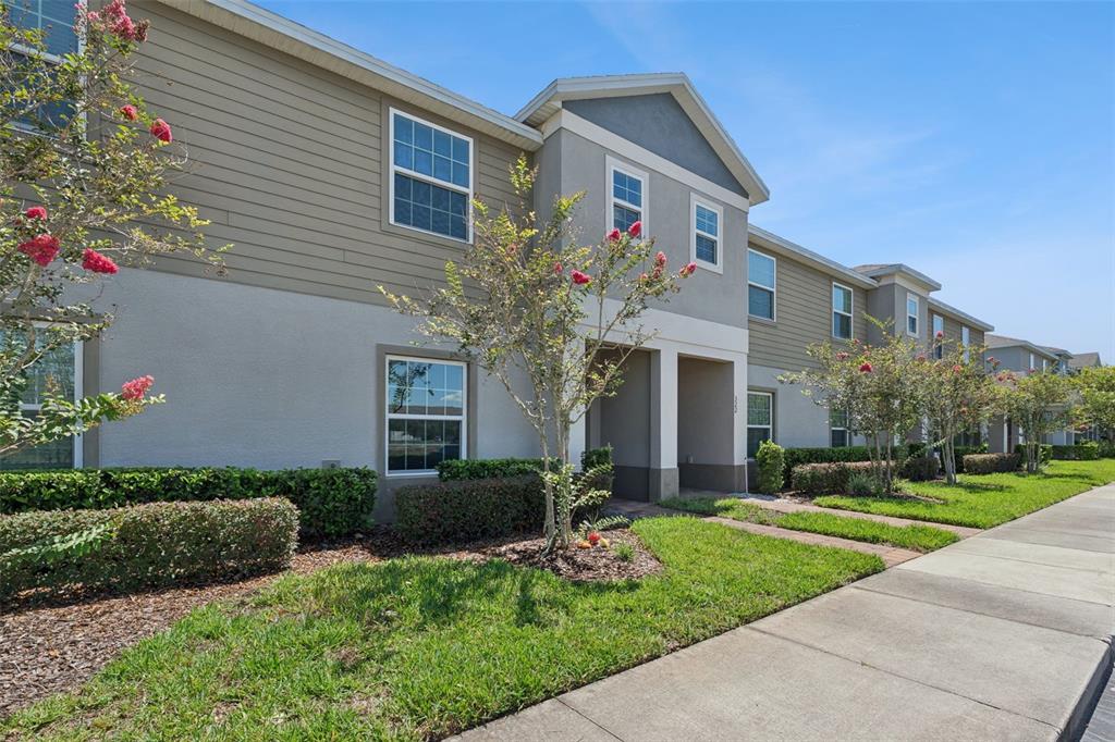 A two-story apartment building with tan siding, stucco walls, and a sidewalk in front — 318 ANNABELLE WAY, DAVENPORT, FL