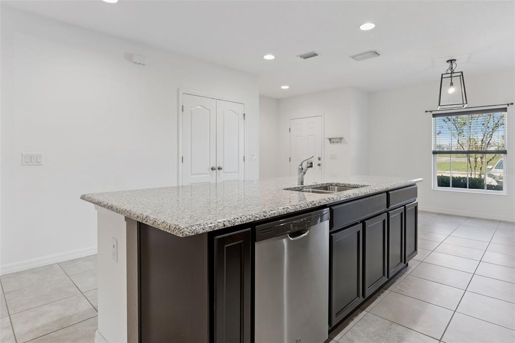 A kitchen island with dark cabinets and granite countertops sits in a room with tile flooring — 318 ANNABELLE WAY, DAVENPORT, FL