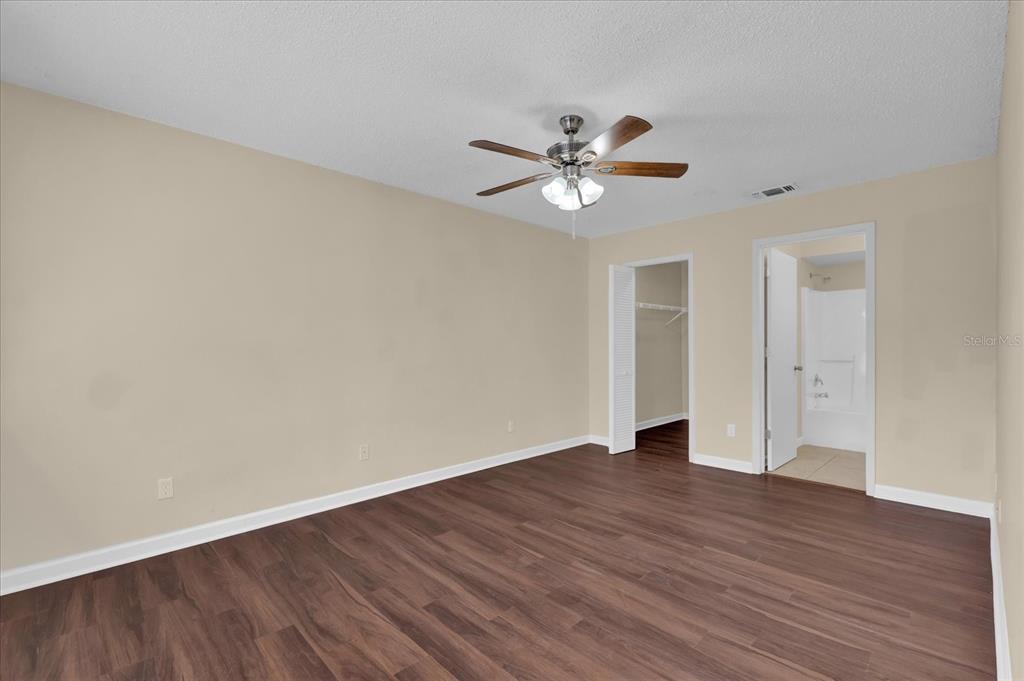 A bedroom features light-colored walls, wood-look flooring, a ceiling fan, a closet, and an ensuite — 2405 NORTHLAKE DRIVE UNIT 2405, SANFORD, FL