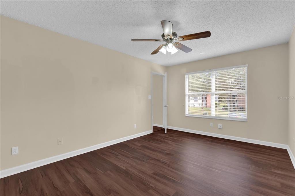 An empty bedroom features beige walls, dark wood-look flooring, a ceiling fan, and a window — 2405 NORTHLAKE DRIVE UNIT 2405, SANFORD, FL