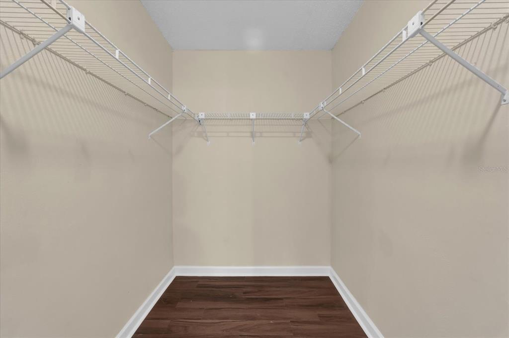A walk-in closet features white wire shelving, beige walls, and dark wood-look flooring — 2405 NORTHLAKE DRIVE UNIT 2405, SANFORD, FL