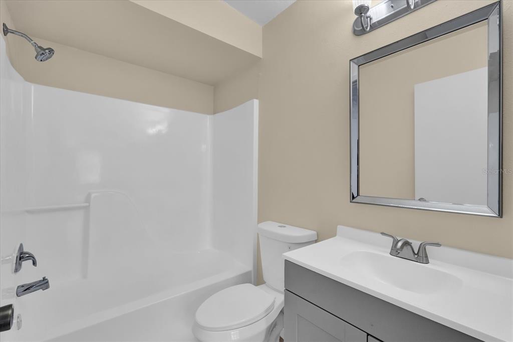 A bathroom features a white tub-shower combo, a toilet, and a vanity with a mirror — 2405 NORTHLAKE DRIVE UNIT 2405, SANFORD, FL