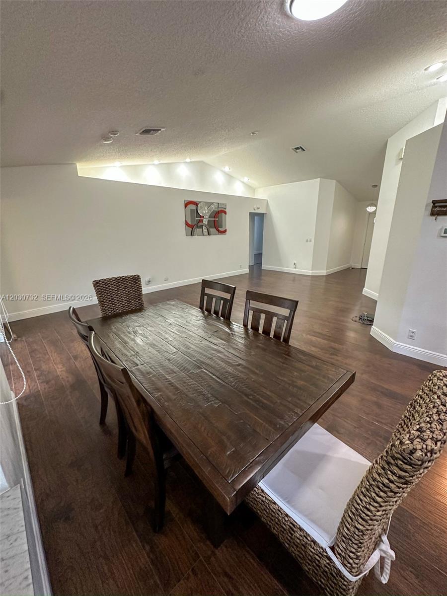 A dining room features a dark wood table, matching chairs, and hardwood flooring — 1010 Salmon Isle, Green Acres FL 33413, GREEN ACRES, FL