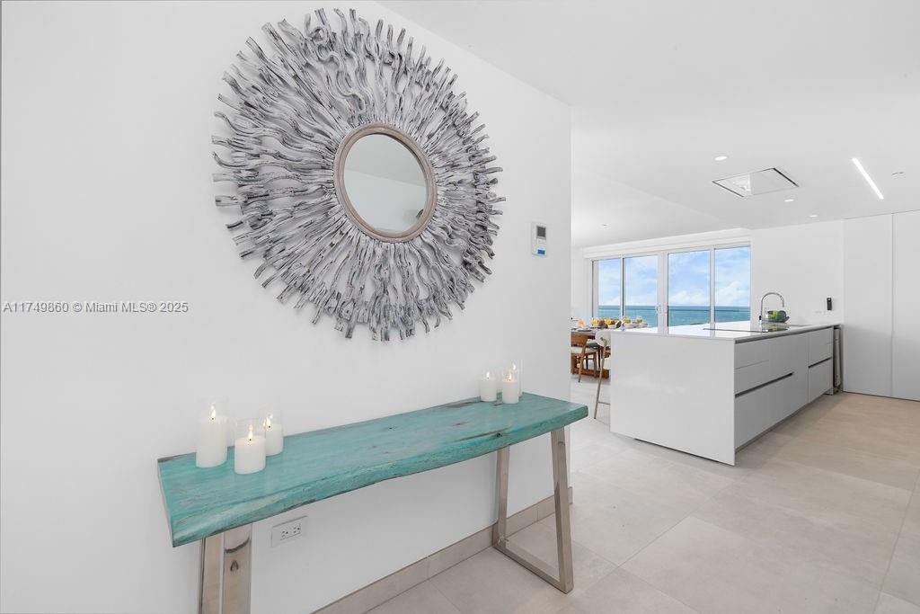 A modern entryway features a turquoise console table, a decorative mirror, and an ocean view — 1 NW IRAUSQUIN BLV # 1A, Au, Au