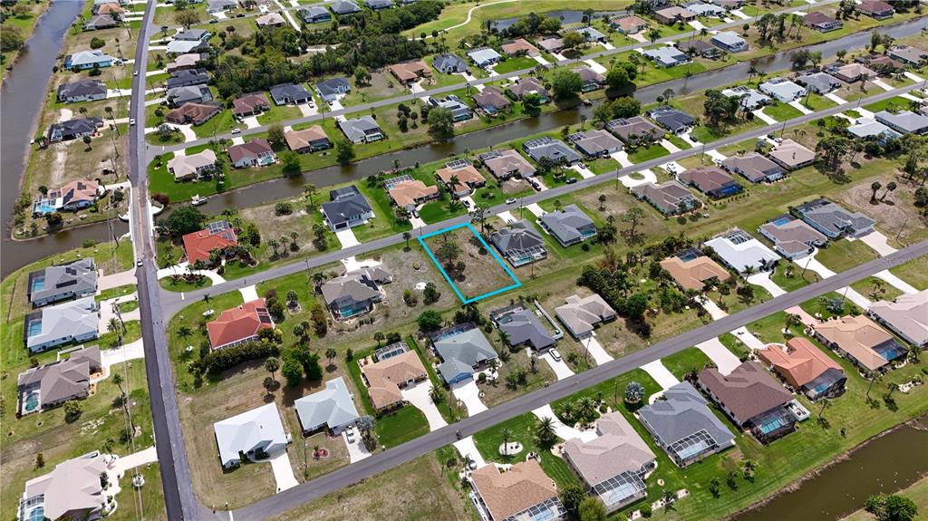 This aerial view shows a vacant residential lot outlined in blue within a suburban neighborhood — 9 LONG MEADOW LANE, ROTONDA WEST, FL