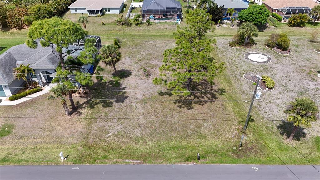 An aerial view shows a vacant residential lot with several trees next to a house — 9 LONG MEADOW LANE, ROTONDA WEST, FL