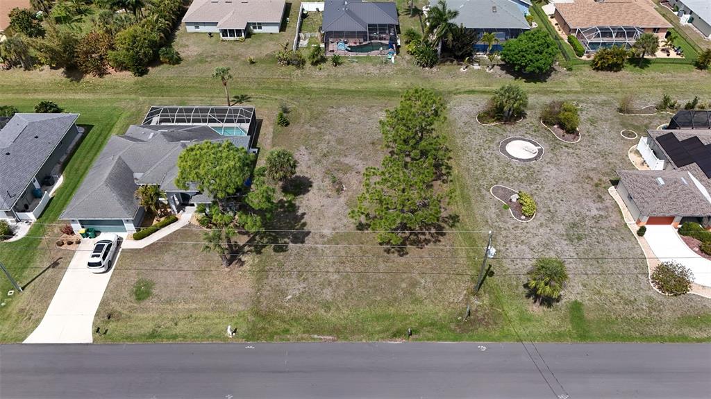 An aerial view shows a vacant residential lot situated between two houses on a street — 9 LONG MEADOW LANE, ROTONDA WEST, FL