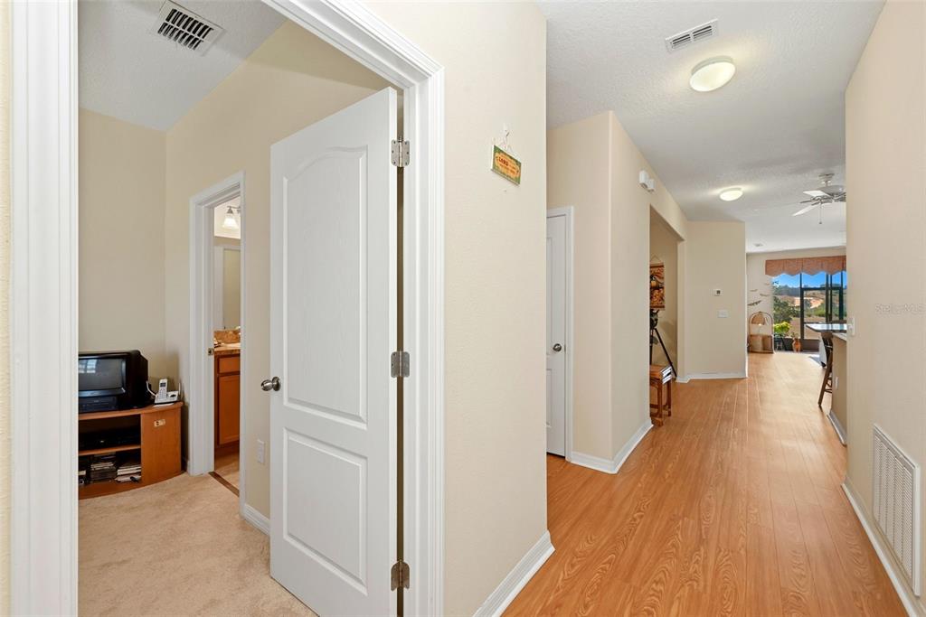 A hallway with wood-look flooring leads to an open living area with a view outside — 3632 SOLANA CIRCLE UNIT B, CLERMONT, FL