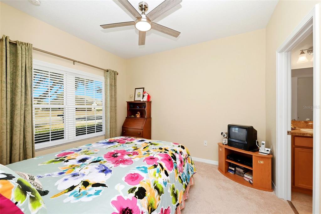 A bedroom features a floral bedspread, a ceiling fan, a wooden hutch, and a television stand — 3632 SOLANA CIRCLE UNIT B, CLERMONT, FL