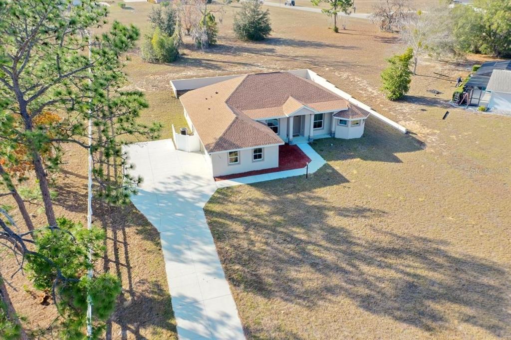 An aerial view shows a single-story house with a brown roof and a concrete driveway — 1464 N HAMBLETONIAN DRIVE, HERNANDO, FL