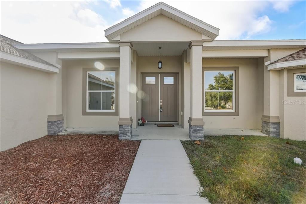 A front exterior view of a house with a covered entryway and double front doors — 1464 N HAMBLETONIAN DRIVE, HERNANDO, FL