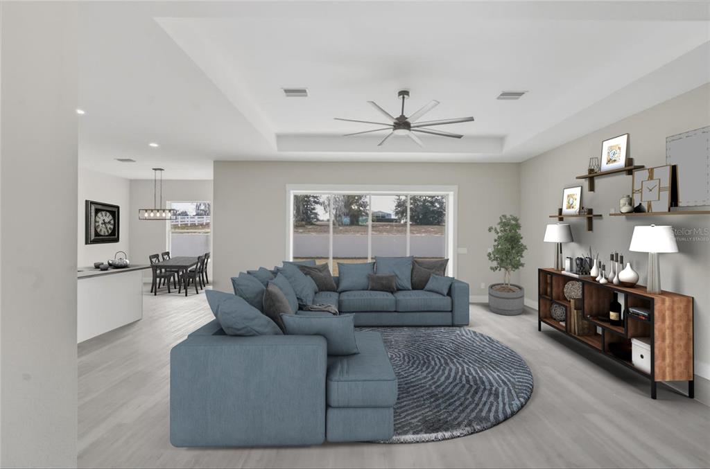 This virtual staging rendering shows a living room with a blue sectional, rug, and shelving — 1464 N HAMBLETONIAN DRIVE, HERNANDO, FL