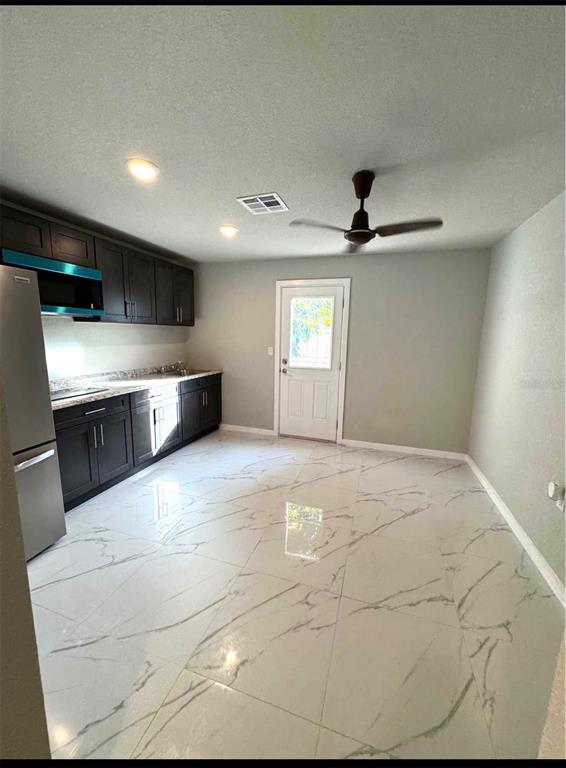 A kitchen with dark cabinets, stainless steel appliances, and white marble-patterned tile flooring — 821 THALIA DRIVE, ORLANDO, FL