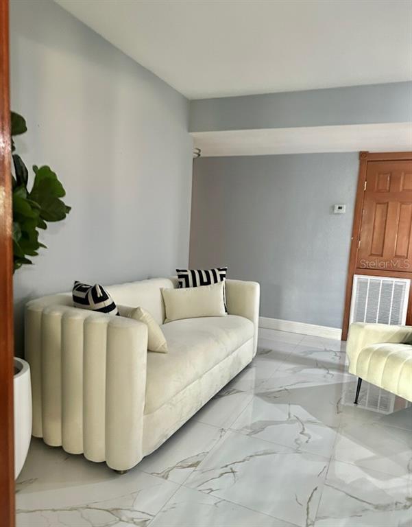 A living room features a cream-colored channel-tufted sofa on white marble-look tile flooring — 821 THALIA DRIVE, ORLANDO, FL