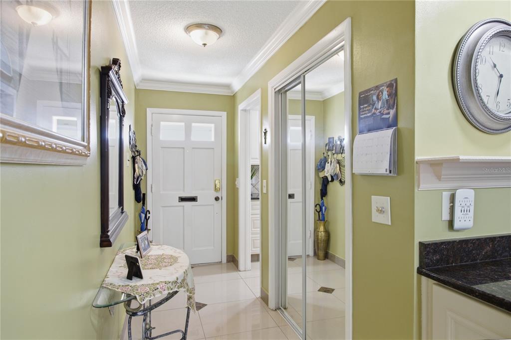 An entryway features light green walls, tiled floors, a white front door, and mirrored closet doors — 1636 S LAKE AVENUE UNIT 1, CLEARWATER, FL