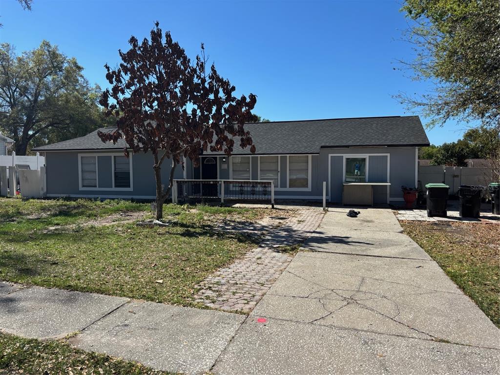 A single-story gray house with a dark roof, a front deck, and a concrete driveway — 5214 GAYMAR DRIVE, ORLANDO, FL