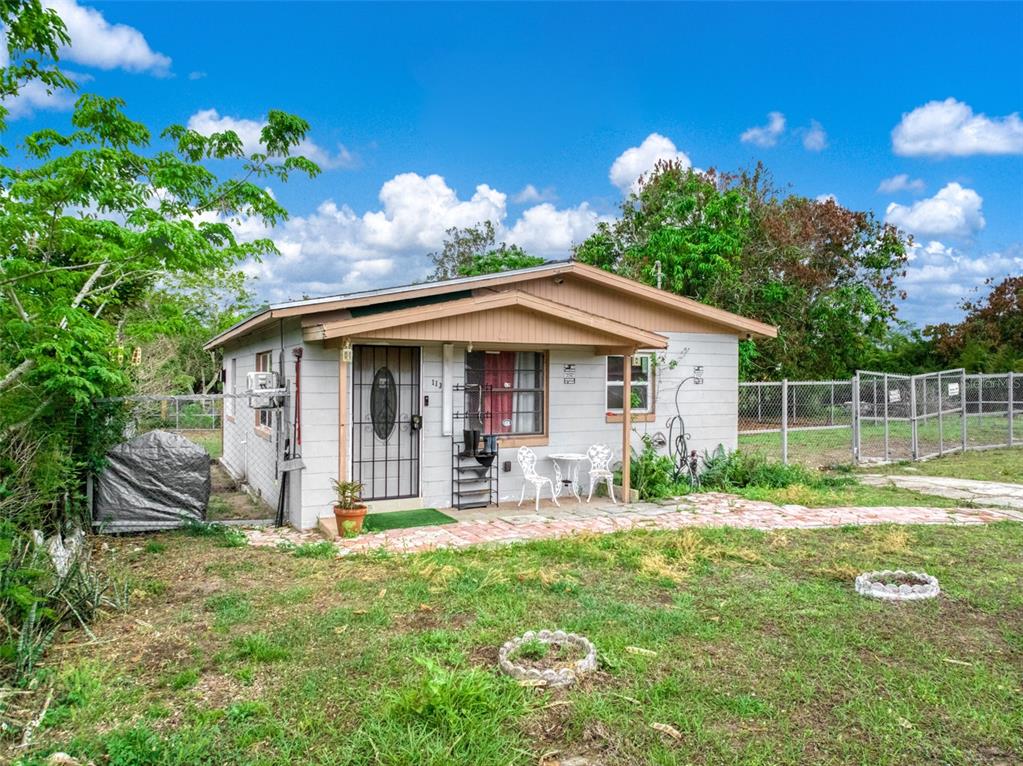 A small, single-story concrete block house with a covered porch and a grassy yard — 113 ANDERSON STREET, LAKE PLACID, FL