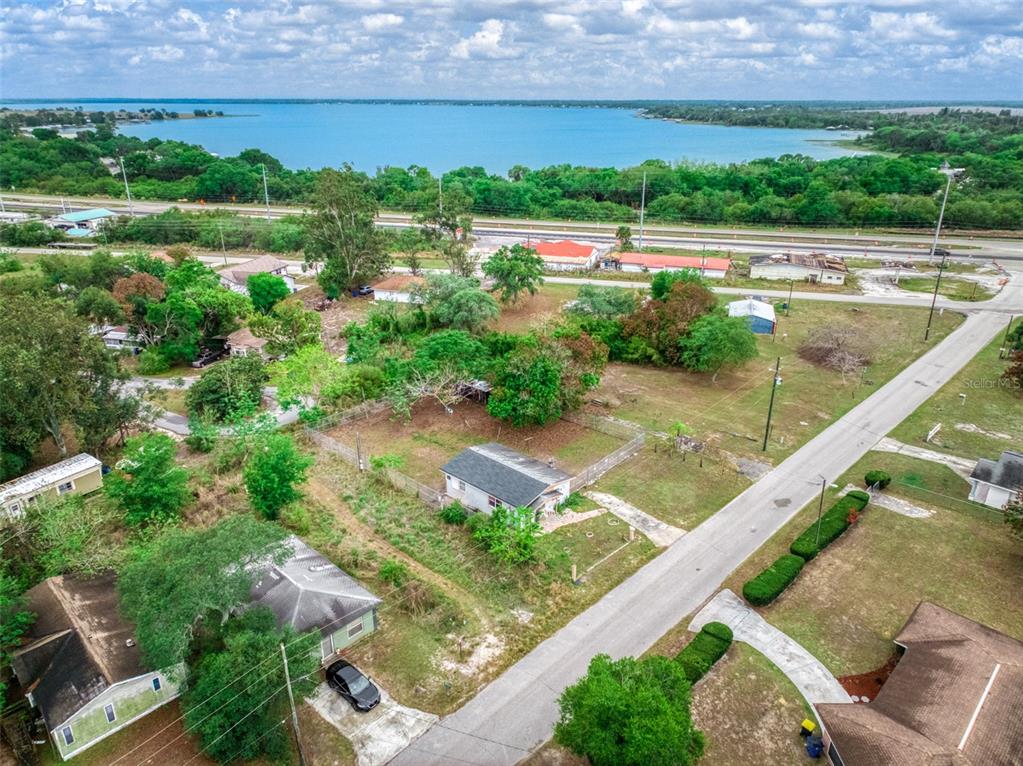 An aerial view shows a residential neighborhood with houses, trees, and a nearby lake — 113 ANDERSON STREET, LAKE PLACID, FL