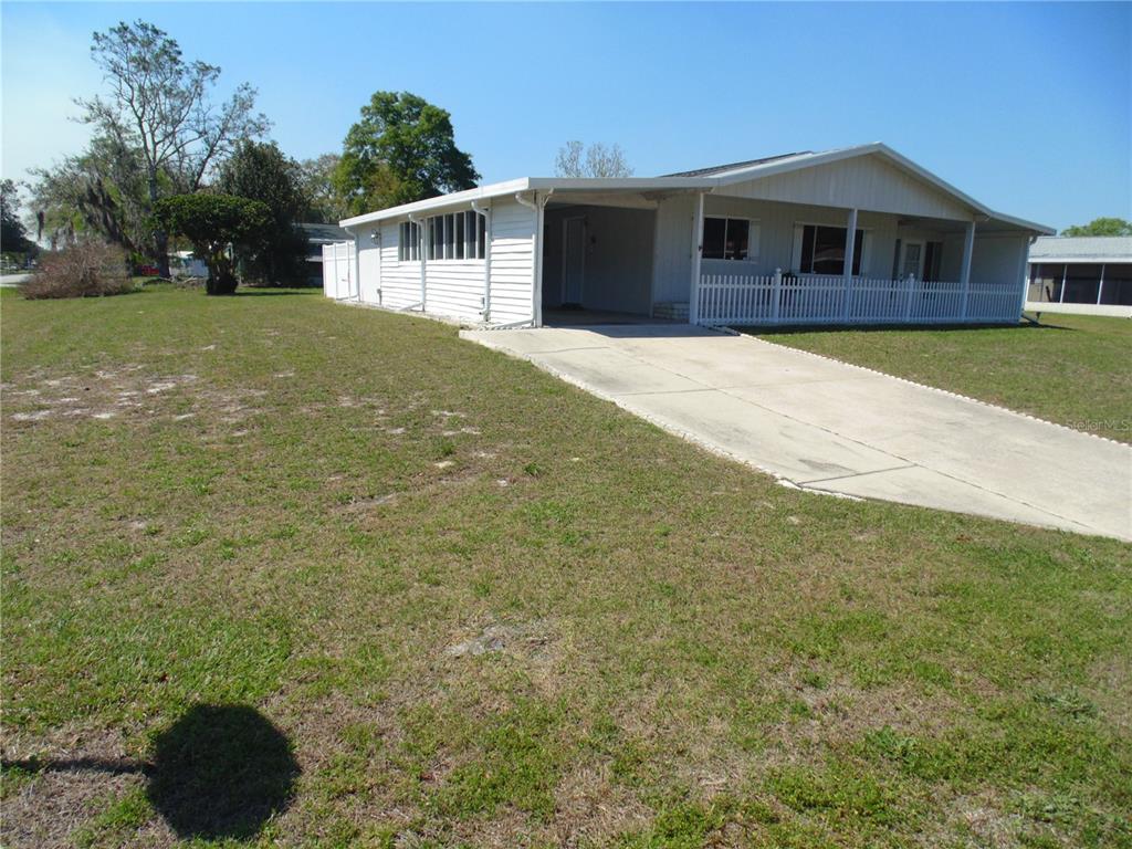 A single-story mobile home with a white exterior, a carport, and a front porch — 10210 SW 93RD AVENUE, OCALA, FL