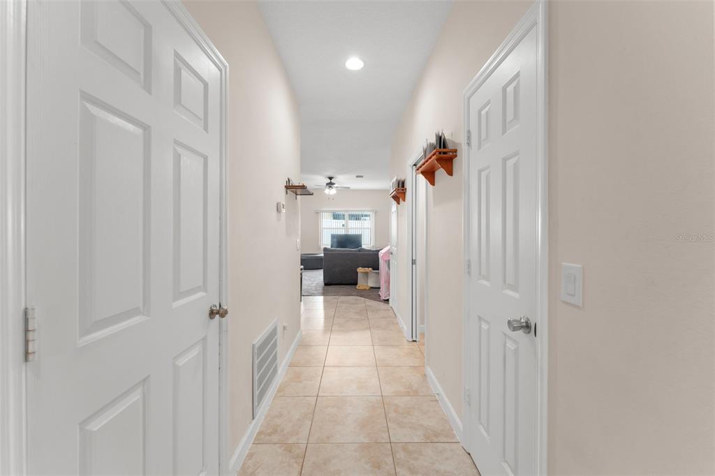 A tiled hallway leads from a doorway toward a living room with a ceiling fan — 1880 PETERSON PLACE, SANFORD, FL