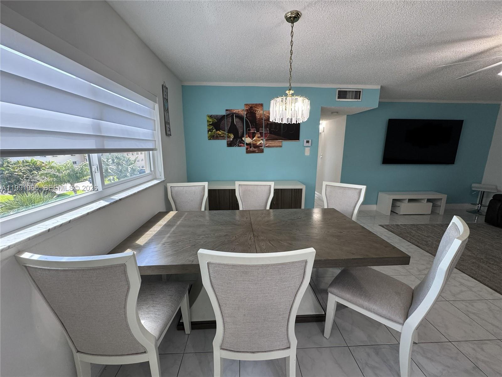 A dining room features a wooden table, six upholstered chairs, and a blue accent wall — 5300 Washington St # V407, Hollywood FL 33021, HOLLYWOOD, FL