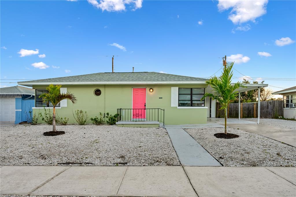 A light green single-story house features a bright pink front door and two palm trees — 1225 GROVE STREET, CLEARWATER, FL