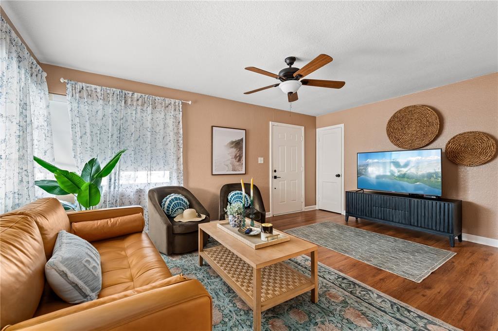 A living room features a tan leather sofa, two armchairs, a coffee table, and television — 1225 GROVE STREET, CLEARWATER, FL