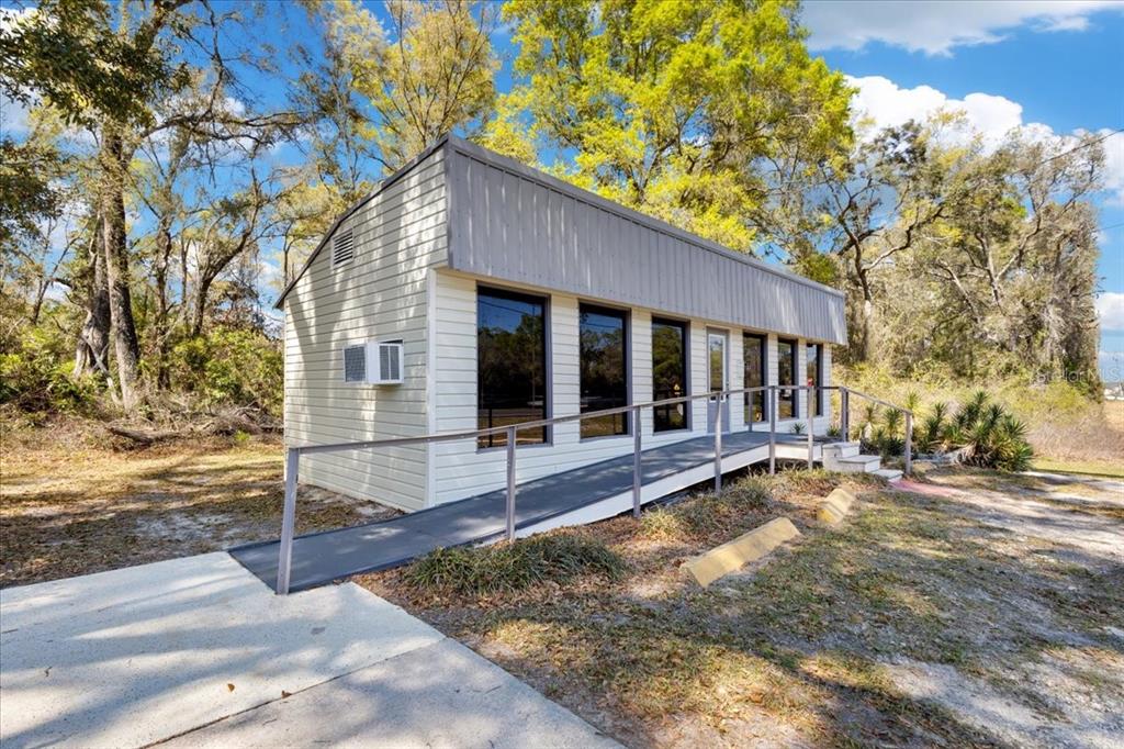 A small, light-colored commercial building features a metal roof, large windows, and a wheelchair ramp — 16648 NW US HIGHWAY 19, TRENTON, FL