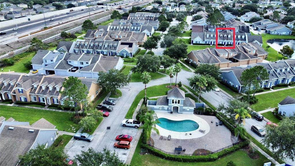 An aerial view shows a community swimming pool surrounded by a patio, landscaping, and parking — 2074 ISLAND WALK DRIVE, ORLANDO, FL