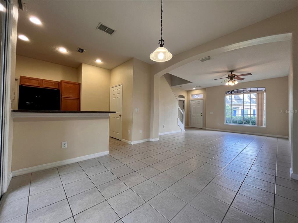 A kitchen features dark countertops, wooden cabinets, black appliances, and light-colored tile flooring — 2074 ISLAND WALK DRIVE, ORLANDO, FL