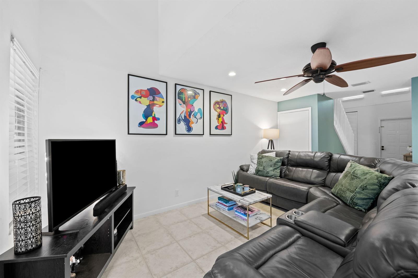A living room features a dark leather sectional, a television console, and colorful wall art — 6706 Boca Pines Trail # C, Boca Raton FL 33433, BOCA RATON, FL