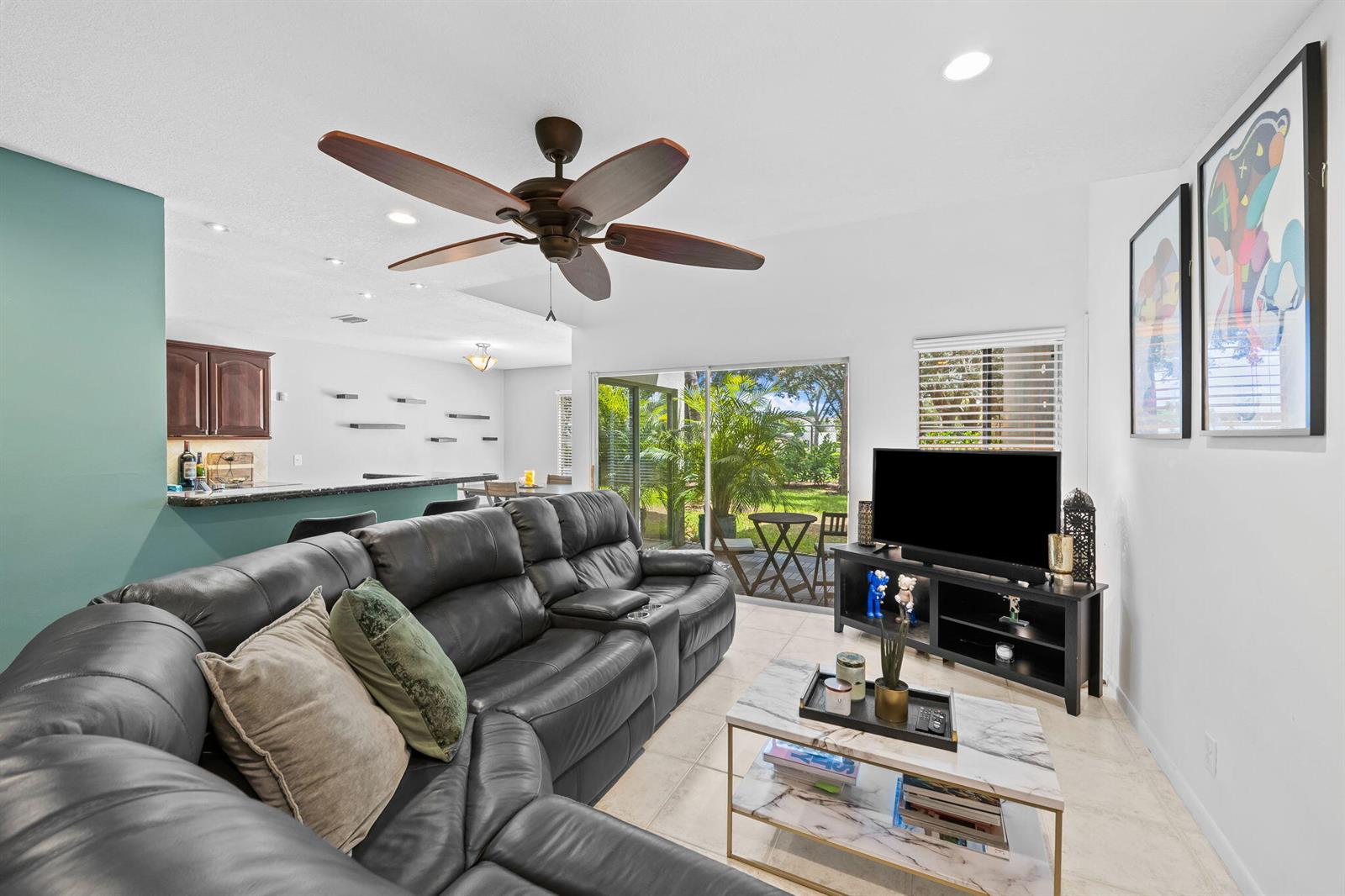 A living room features a dark leather sectional, marble coffee table, and sliding glass doors — 6706 Boca Pines Trail # C, Boca Raton FL 33433, BOCA RATON, FL