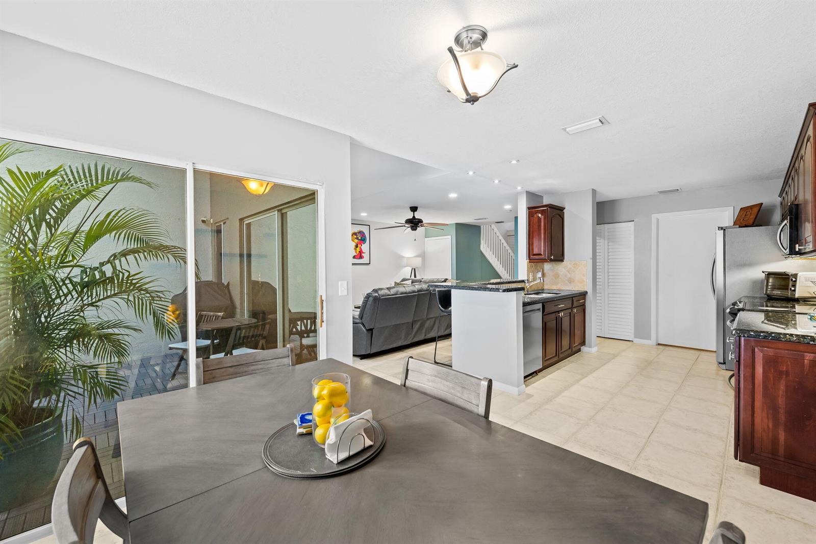 A dining area with a gray table overlooks a patio, kitchen, and living room — 6706 Boca Pines Trail # C, Boca Raton FL 33433, BOCA RATON, FL