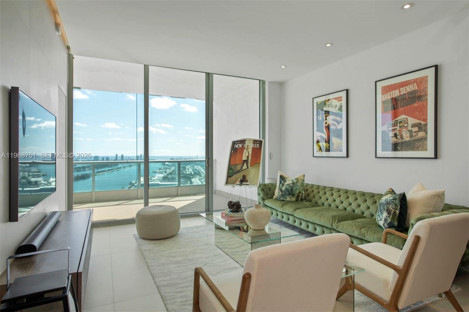 A modern living room features a green tufted sofa, two armchairs, and floor-to-ceiling windows — 900 Biscayne Blvd # 4307, Miami FL 33132, MIAMI, FL